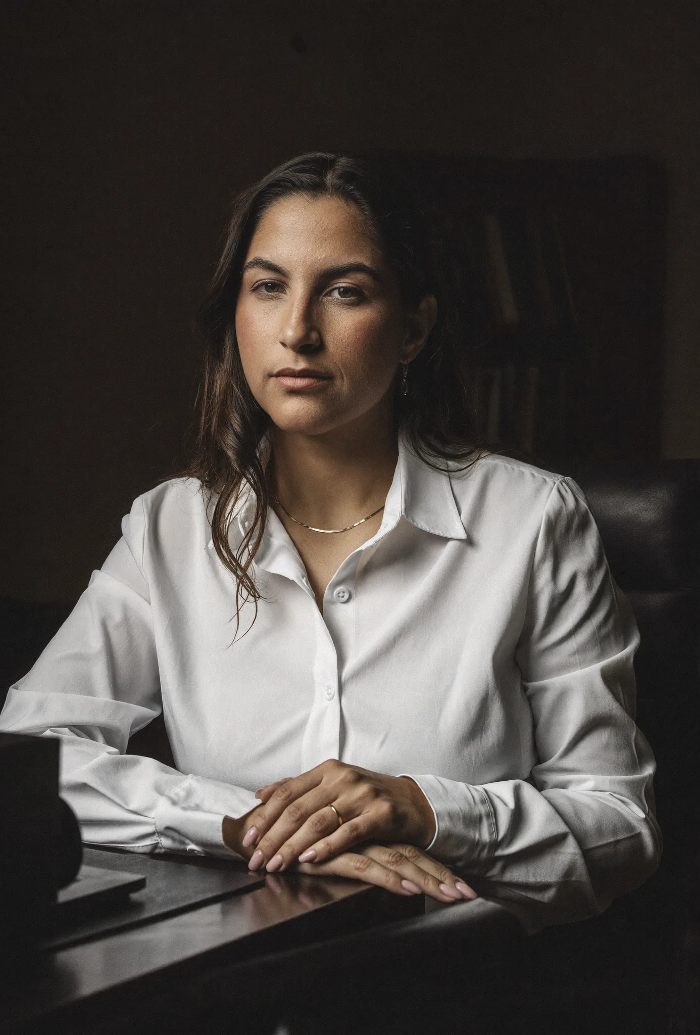 Jennifer Paim, advogada criminalista, sentada à mesa do escritório, olhando de frente